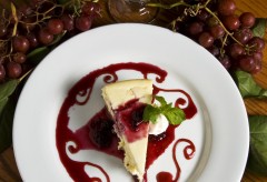 A slice of cheesecake drizzled with a fruity topping.