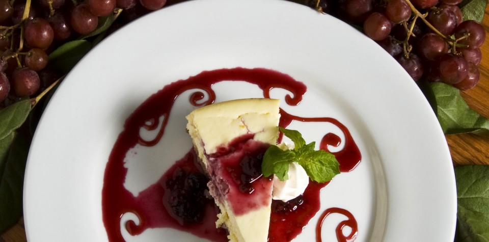 A slice of cheesecake drizzled with a fruity topping.