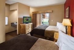 Double queen beds, with a dresser with a tv, and patio access