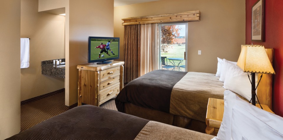 Double queen beds, with a dresser with a tv, and patio access
