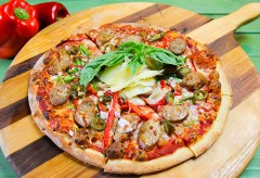A hot sausage pizza topped with fresh basil.