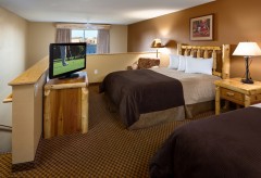 Two queen beds with a night stand in between and a tv and dresser