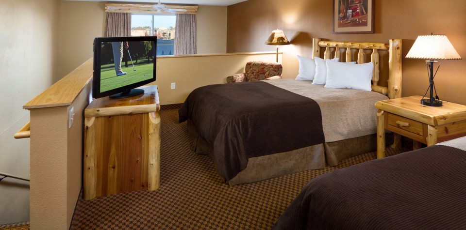 Two queen beds with a night stand in between and a tv and dresser
